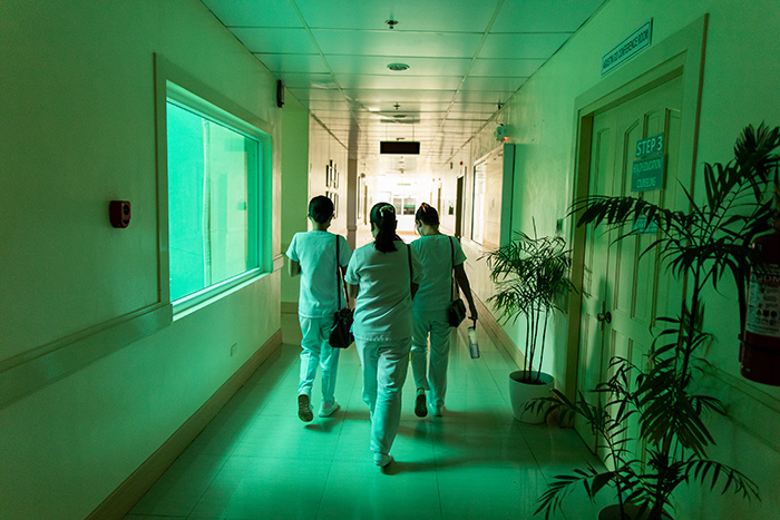 Group of nurses walk down green-lit hallway